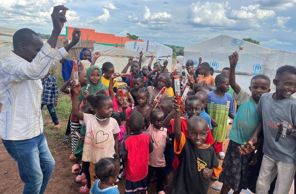 أطفال سودانيون لاجئون في يوغندا يحملون هدايا تلقوها بمناسبة عيد الفطر المبارك.